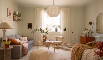 A sage green studio home with a kitchen decorated with lots of plants