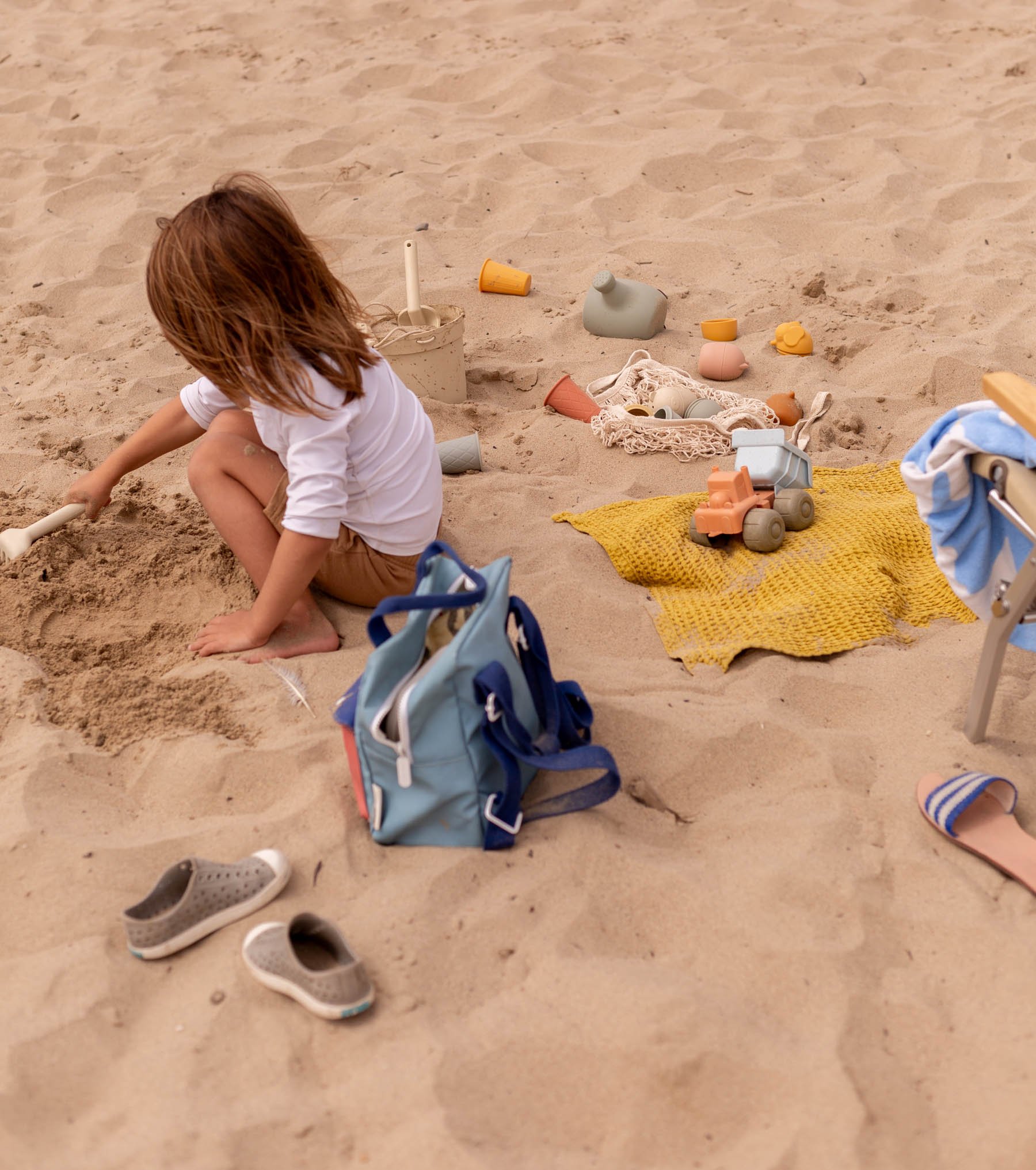 young child playing in sand at beach with neutral sand toys