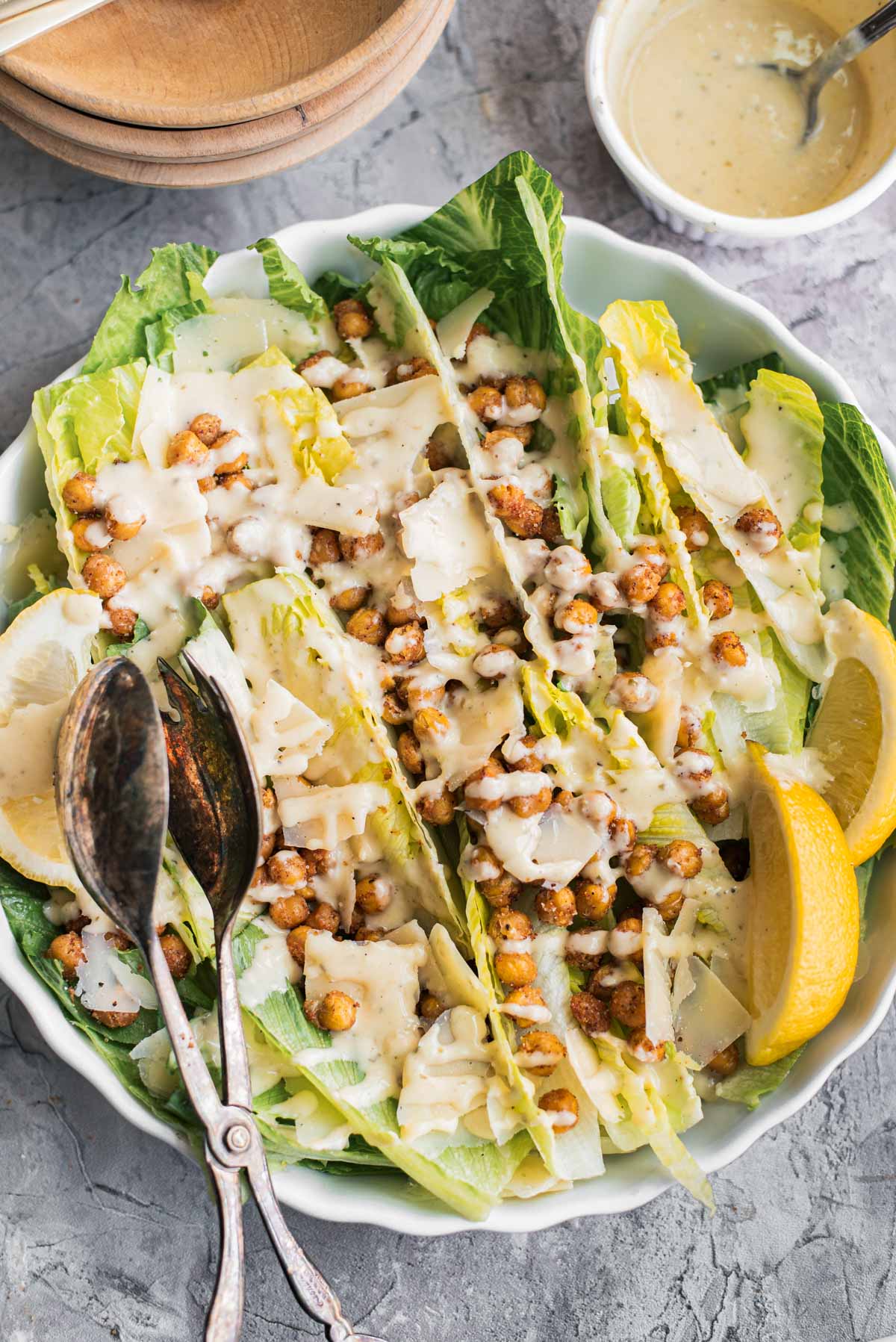 roasted chickpea salad in a large bowl with serving tongs and small bowls ready to serve
