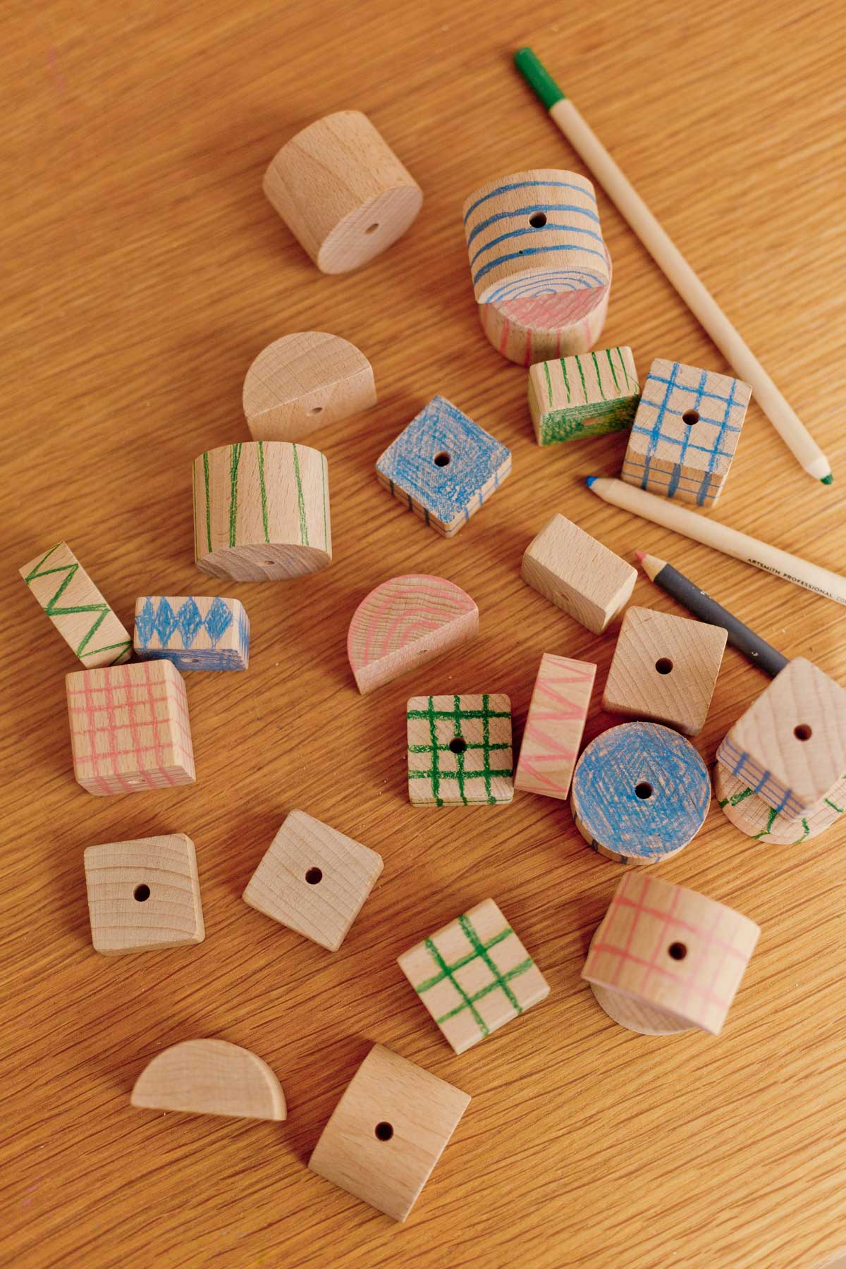 scattered wood blocks on a wood table with colored pencils