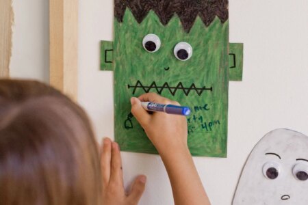 young child drawing on a halloween dry erase board that is on the wall