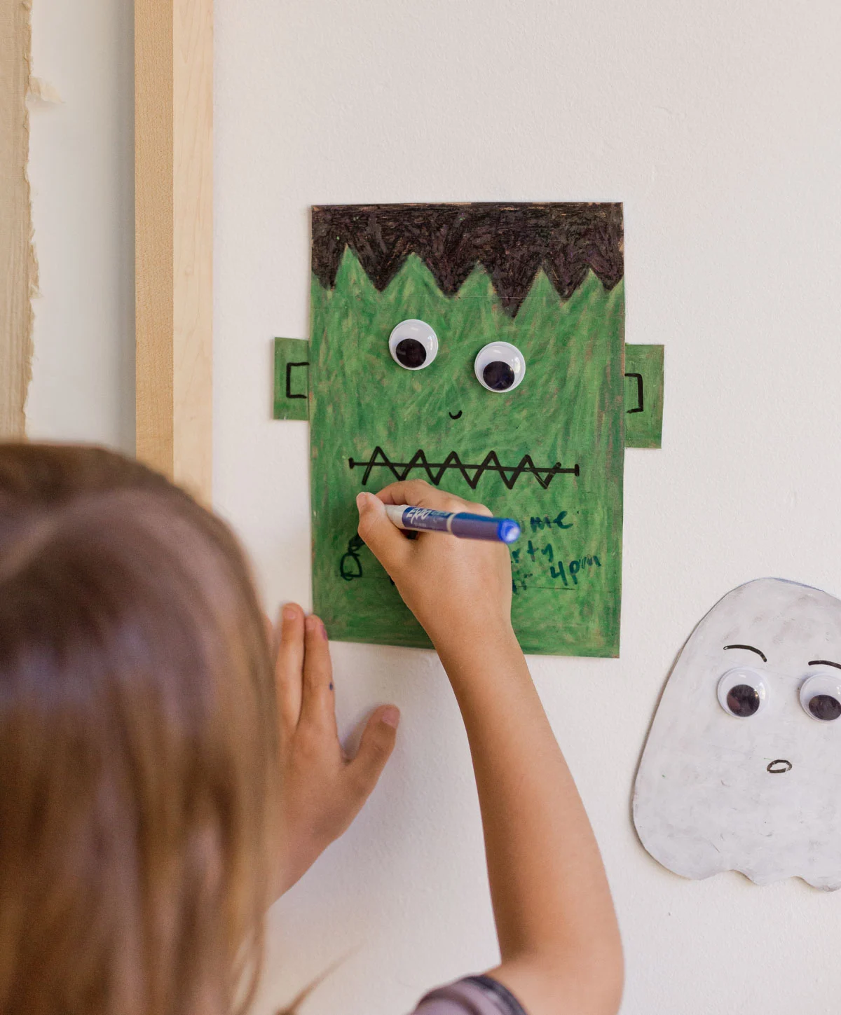 young child drawing on a halloween dry erase board that is on the wall